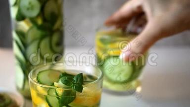 清爽的夏季饮料，柠檬，生姜，新鲜<strong>黄瓜</strong>和薄荷。 女人`手把杯子和<strong>柠檬水</strong>放在桌子上。